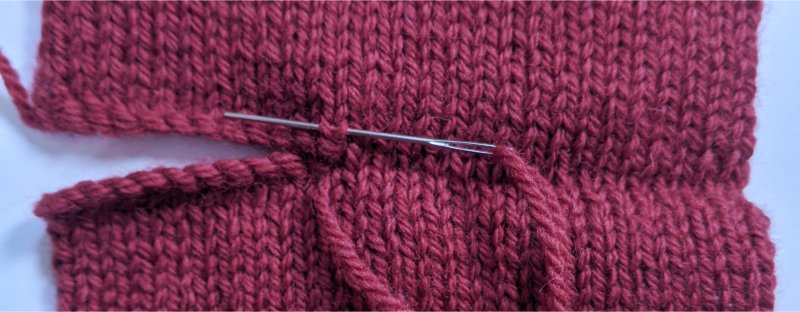 Grafting the top and bottom of two knitted squares together with a sewing needle