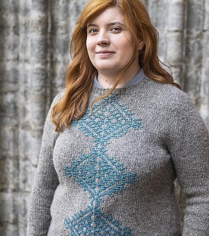 a grey sweater with a large teal motif on the front, made using the roosimine technique