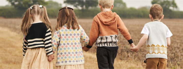 Four children wearing colorful jumpers, holding hands and walking into the distance