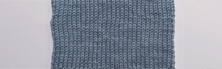 The center section of a stockinette swatch knitted in a blue/gray shade using Rowan Cotton Glacé. The stitches are neat, although not 100% regular.