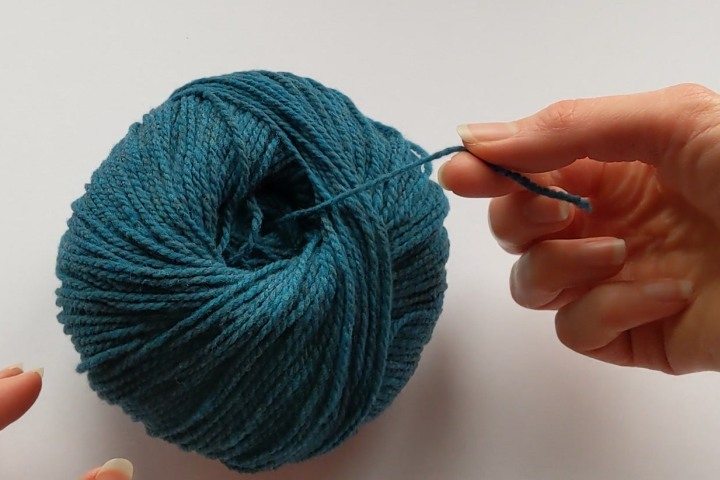 A center-pull ball of yarn being pulled